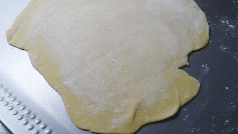 自製雞蛋麵條,麵皮桿好後，準備粘板和菜刀，用手粉輕撫麵皮讓兩個表面都不沾黏後，對折兩次，比較好切。