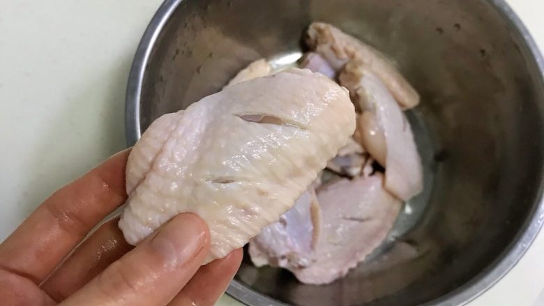 韩式吮指炸鸡翅,为了鸡翅更快更好的入味，用刀在鸡翅面上划2-3刀。