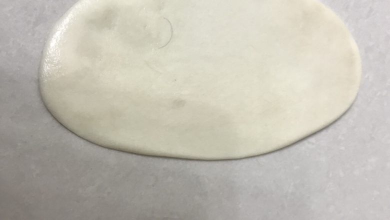 芝麻小脆饼,取一个面团用手掌压一下再用擀面杖擀成长舌形。