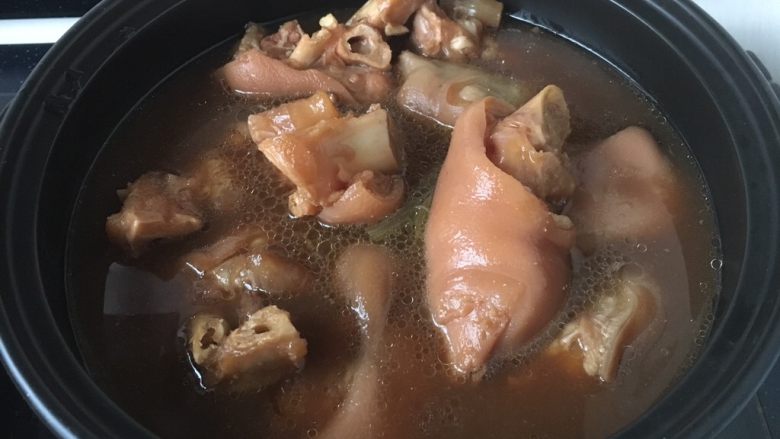 黑豆黄豆猪手煲,将适量的煮过的猪手和汤倒入砂锅里。