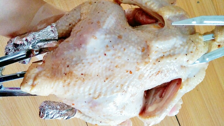 家庭版烤鸡,用锡纸把鸡翅尖和鸡腿骨包起来，以防烤糊了，再用烤叉把鸡串起来