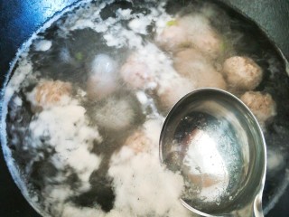 小白菜丸子汤,用勺子撇去汤表面的浮沫