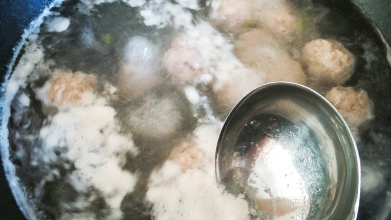 小白菜丸子汤,用勺子撇去汤表面的浮沫