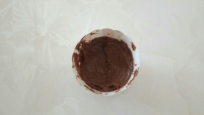 可可味巧克力流心马芬,取1/3可可面糊倒入纸杯中，用勺子挖个坑。