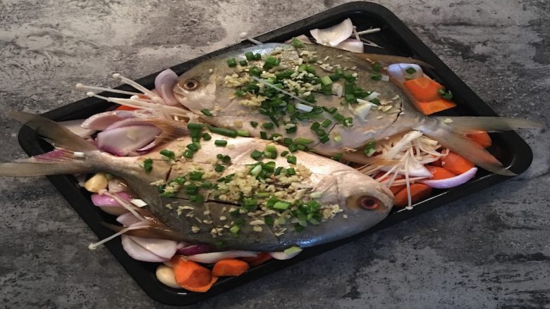 健身减脂杂蔬烤海鱼,用刷子在鱼生刷一层薄油后放入烤盘，并在鱼身撒上少许姜蒜末；