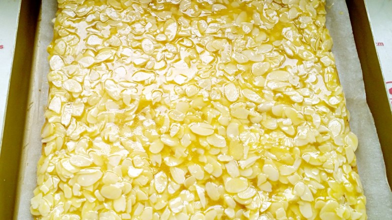 焦糖杏仁酥,趁热将杏仁片均匀铺在酥饼表面并轻轻压平。