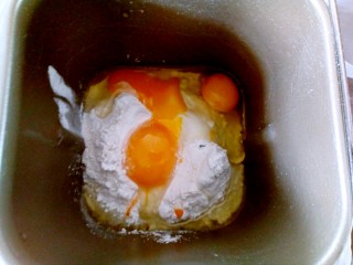 蔓越莓沙琪玛,将面粉、泡打粉和鸡蛋倒入面包机桶中。