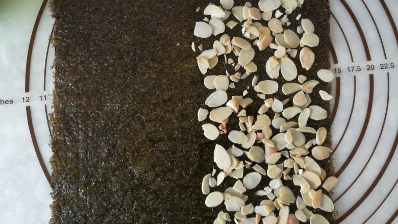 海苔杏仁脆片,然后铺上保温的杏仁片，铺的均匀些，尽量在一个平面上尽量不要有叠加，会影响后面压平。再撒上保温的白芝麻，这里说明一下，不是坚果越多越好吃，铺的太多会吃不出海苔的酥脆，所以适量就好