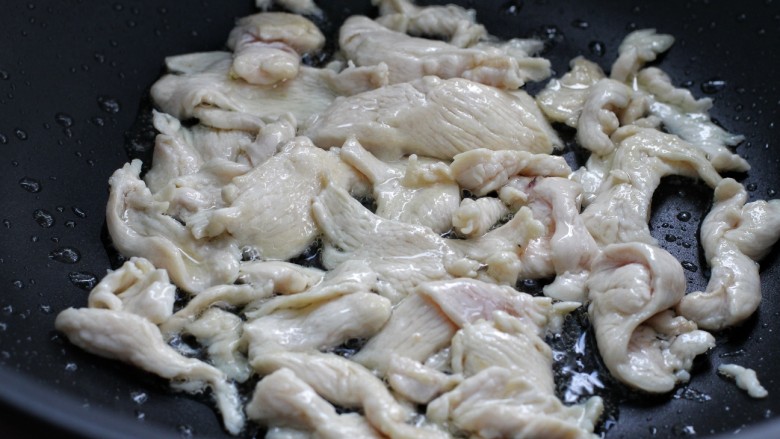 西芹火腿炒鸡片,锅中倒25克食用油油烧热后放入鸡片，翻炒至发白变色状态，盛出备用