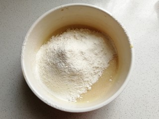 抹茶猫咪甜甜圈,面粉和泡打粉混合过筛到蛋液中，然后再用搅拌刀翻拌至无干粉状态。