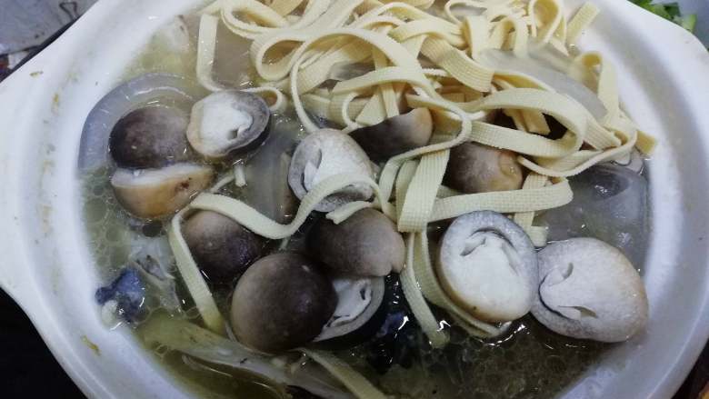 千岛湖鱼头汤,厚百叶切丝捞烫后，与粉皮和草菇一起倒入鱼头汤，开小火继续煲煮。