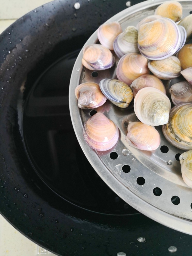 爆炒花蛤,锅中加入冷水。蒸隔放上洗净的花蛤