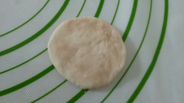 仿真蘑菇豆沙包,取一个香菇包面团，团圆，用手压扁，捏成中间后两边薄的片。