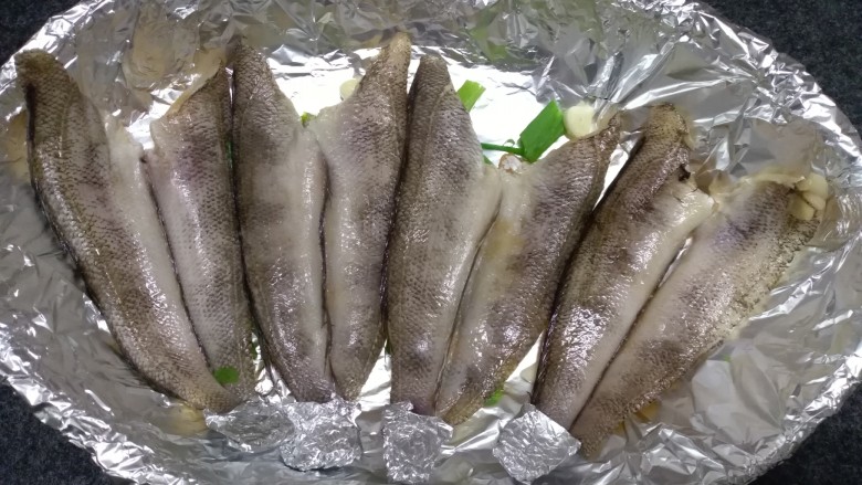 烤箱版烧烤南极冰鱼,放入腌制好的鱼，腌制的料不要。鱼尾用锡纸包裹住，因为烤至过程中容易糊。
