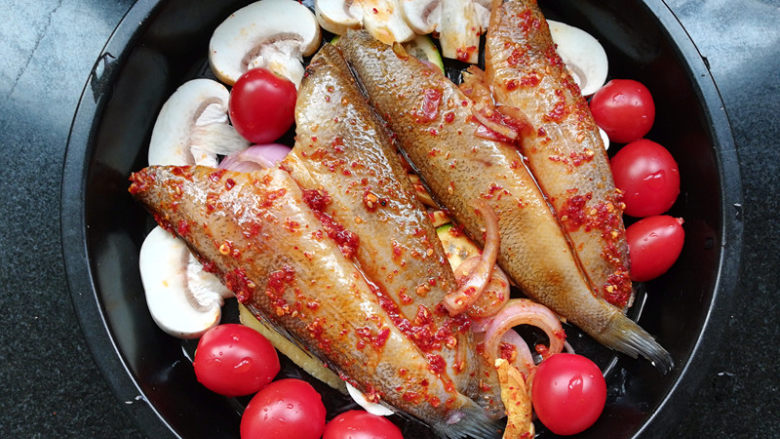柠檬香辣烤冰鱼,将鱼摆放在蔬菜上面，倒入腌鱼的汤汁。摆上几个千禧。