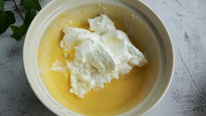 芝麻戚风蛋糕,盛三分之一蛋白到蛋黄碗里，从底部往上翻拌，不要画圈搅拌。