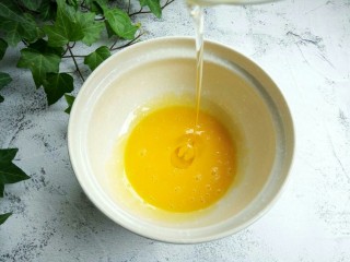 芝麻戚风蛋糕,先将鸡蛋的蛋黄和蛋白分开，今天用了5个鸡蛋，带壳的总重量是265克左右，鸡蛋的总重量最好控制在260–270之间，盛蛋白的碗需要无油无水。蛋黄先用打蛋器搅拌均匀，再加入加拿大芥花油，用打蛋器搅打到混合均匀。加拿大芥花油味道清淡，做烘焙是最好的原料，做好的戚风蛋糕更加地香。