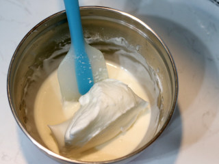 低脂豆乳天使蛋糕卷,先取一部分打发好的蛋白与【步骤2】的面糊小心翻拌均匀。