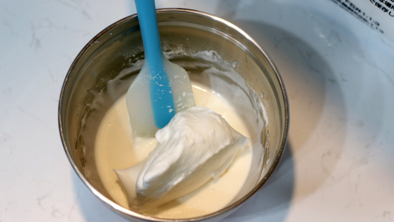 低脂豆乳天使蛋糕卷,先取一部分打发好的蛋白与【步骤2】的面糊小心翻拌均匀。