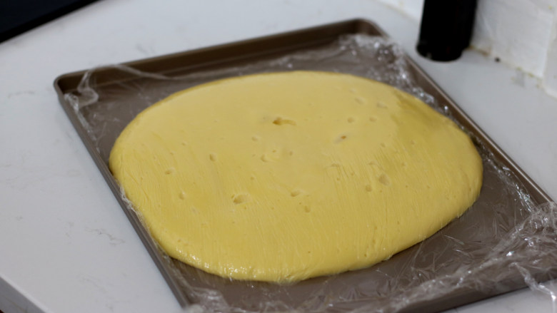 低脂豆乳天使蛋糕卷,倒入不粘烤盘中，摊开后，保鲜膜贴面保存放凉备用。