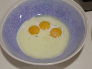 肉松小贝,在蛋黄碗里加入配方中的牛奶、10克糖、油、盐。