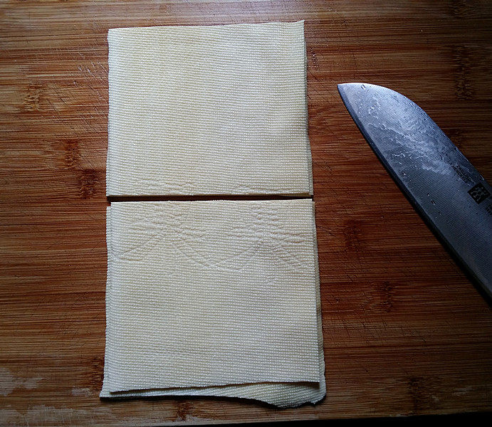 苜蓿香肠百叶卷,将买来的整张豆皮用水冲洗干净、一折为三叠成长条、中间切一刀成正方形