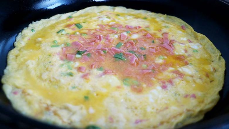 爱心营养早餐首选--厚蛋烧,将平底锅中放入一点油,转小火倒入一层蛋液,转动锅子使其流平蛋液未完全凝固前从一边起起卷起。