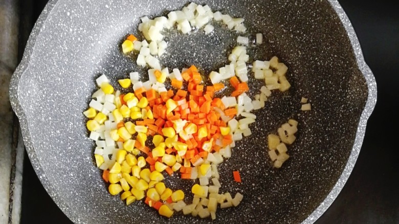 彩蔬奶酪小丸子,倒入胡萝卜和玉米粒翻炒至全熟