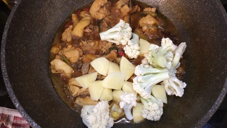 大盘鸡,开盖倒入花椰菜和土豆，继续盖上锅盖，中火煮至土豆熟烂