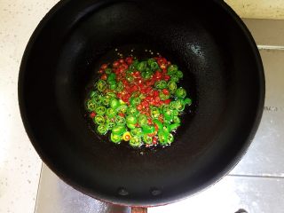 剁椒鸡翅,待油六成热时放入之前准备好的小米椒碎和杭椒碎，然后关火。
