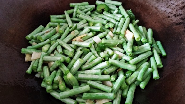 青椒煸豇豆,豇豆炒至变色，盖上盖子小火煸，10秒解开锅盖，翻一次，如此重复直到豇豆煸熟。