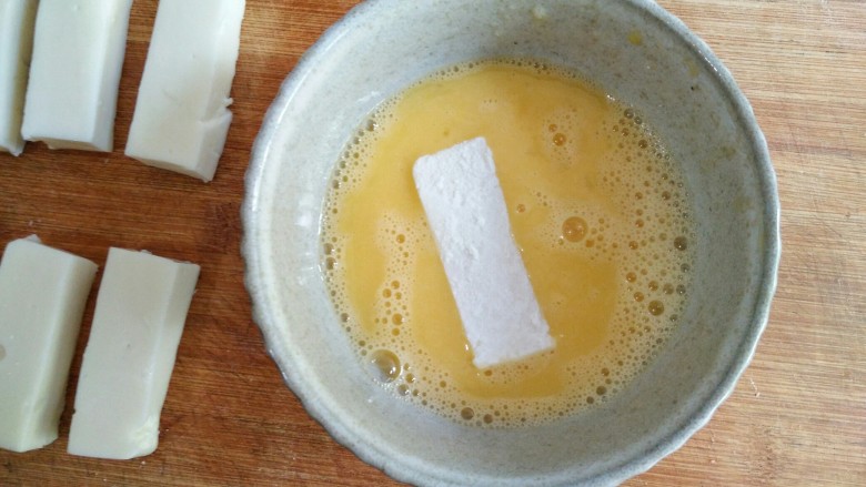 论牛奶的各种吃法之――脆皮炸鲜奶,将<a style='color:red;display:inline-block;' href='/shicai/ 9'>鸡蛋</a>打散成蛋液，将粘了裹炸粉的奶冻条蘸一层均匀的蛋液。