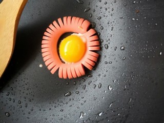 【童趣早餐】,将蛋黄放入火腿肠中间煎熟，这样火腿肠太阳煎蛋就做好了。