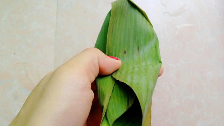 杂豆蜜枣小米粽,如图这样两边的粽叶往中间压，盖住小米