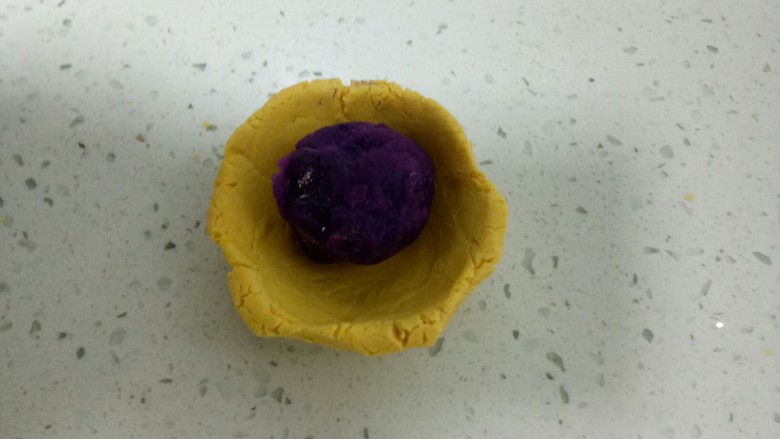 两种口味的糯米南瓜饼,取一个小剂子用拇指按压成碗状，包入紫薯馅。