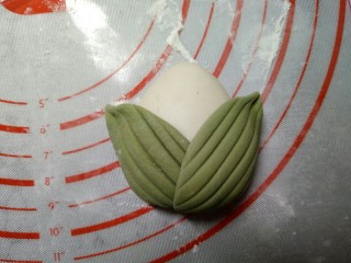 萌粽豆沙包,用同样的方法做好两个叶子，然后背面蘸点水，贴在白色面团上。