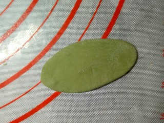 萌粽豆沙包,取约6克一个的绿色面团，搓成两头尖的锥形，再用刮板压扁。