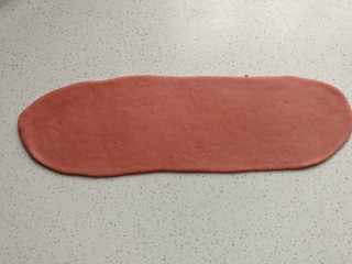 花环豆沙包,再取一份红面团，先搓成圆柱状，再擀成较宽的长舌状。
