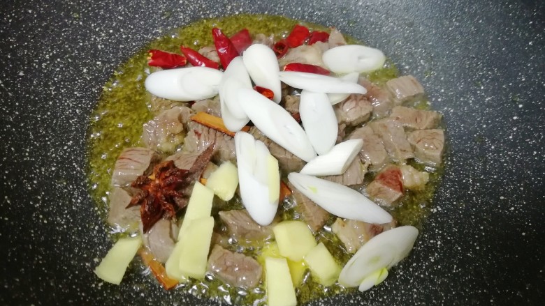 土豆烧牛肉,下入葱、姜、干红辣椒、八角和桂皮炒香。