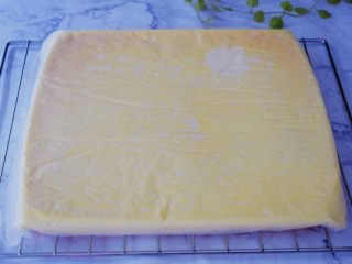 奶油蛋糕卷,烤好后上面铺上新油纸，再把烤网放在蛋糕上，然后倒扣于烤网上
