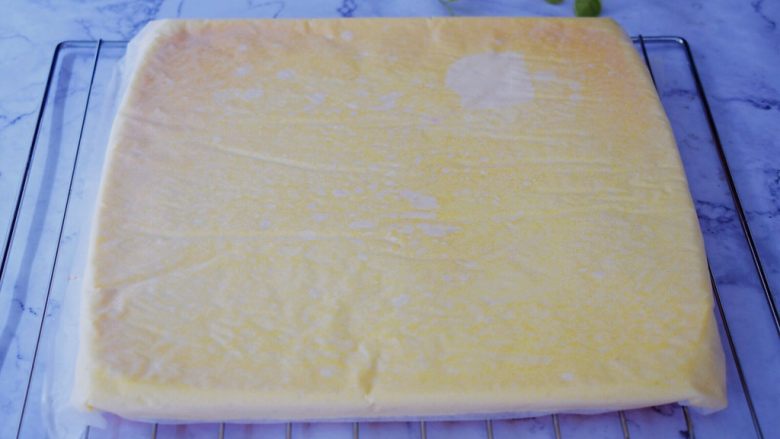 奶油蛋糕卷,烤好后上面铺上新油纸，再把烤网放在蛋糕上，然后倒扣于烤网上