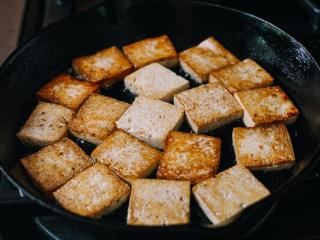 豆豉豆腐,高温加热锅，直到它开始冒烟。这是防止豆腐粘连的重要步骤。把火调到中火，在锅上加两汤匙油。将豆腐两面煎至金黄色。关火，把豆腐放到盘子里。
