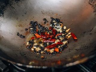 豆豉豆腐, 用中火加热，在锅中加入1勺油，再加入大蒜、豆豉、葱头和碎辣椒。 