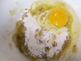 美味下午茶小点心甜糯香蕉饼,将装香蕉泥的碗中打入1颗鸡蛋，然后放入适量的面粉，放入容器中一起再用打蛋器搅拌均匀。