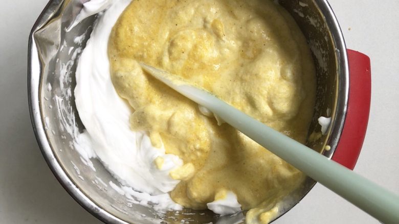 玉米面椰蓉蒸糕,将第8步的面糊倒入剩下的蛋白霜，同样的手法翻拌，切忌用打圈的方式搅拌