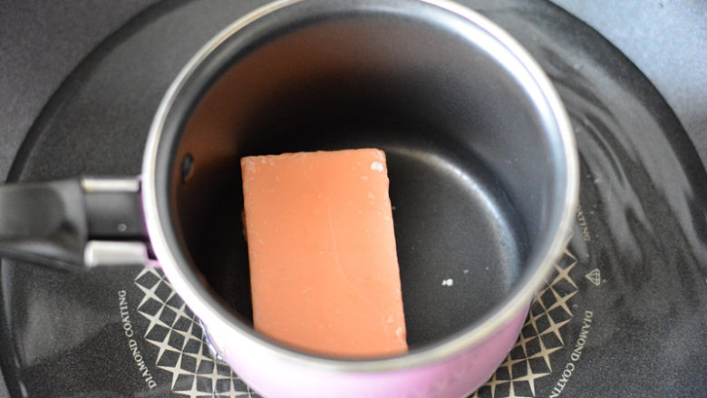 巧克力棒棒糖,在小奶锅里放入草莓味巧克力慢慢搅拌至完全融化，这个过程要用小火，温度过高巧克力会出现起砂的状态，就不能用了