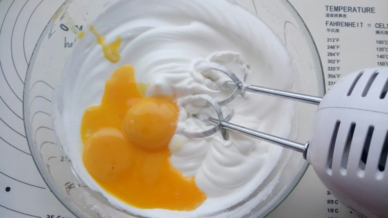 向日葵纸杯蛋糕 ,加入蛋黄继续用电动打蛋器打发。
