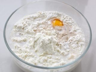 发面红糖饼,面粉放入容器中，再加入鸡蛋、奶粉、酵母、玉米油和温水