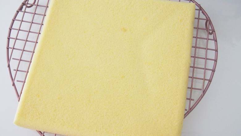 芒果奶油卷,烤好的蛋糕倒扣晾至温热，此时撕下高温油布，盖上一层油纸防止表面变干燥