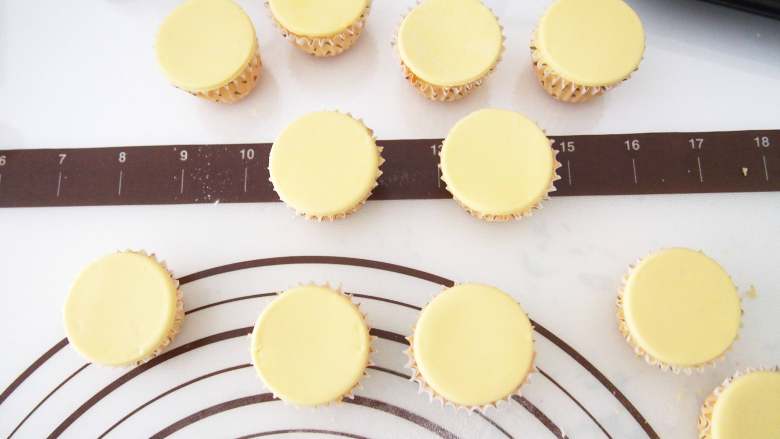 小黄人酸奶蛋糕,翻糖用黄色色素调成黄色，擀成薄片后用模具压出与纸杯大小一致的圆形，刷一层糖浆或者奶油霜固定在蛋糕表面
